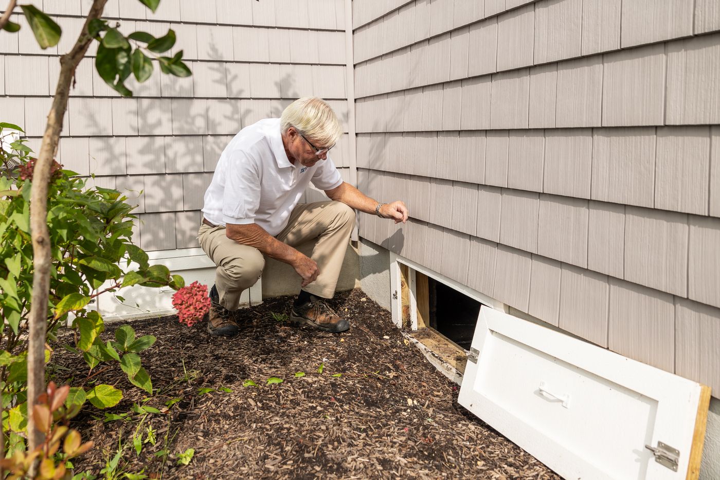 A local exterminator inspecting the foundation and crawl space of a home for pests